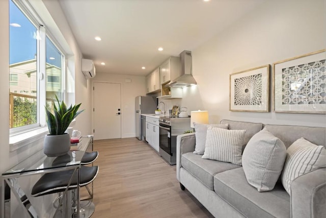 living room with sink, a wall mounted AC, and light hardwood / wood-style floors