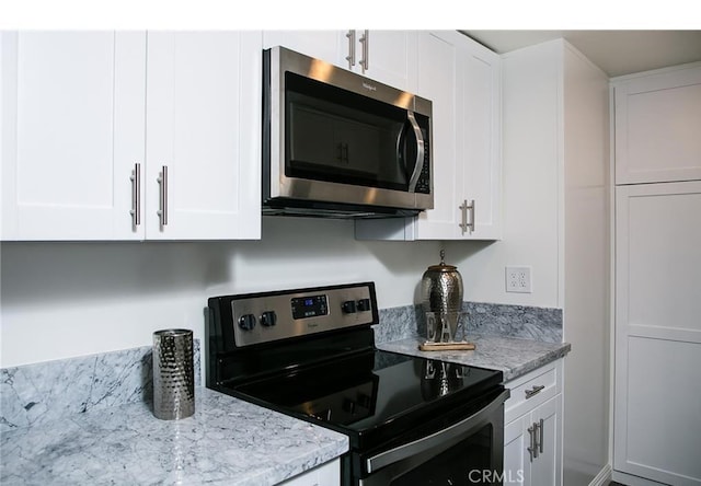 kitchen with white cabinetry, light stone countertops, and appliances with stainless steel finishes