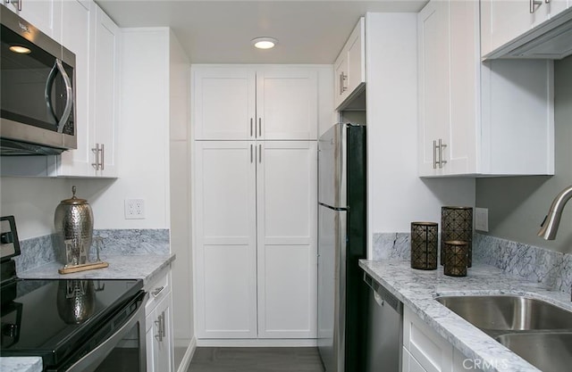 kitchen featuring light stone counters, sink, white cabinets, and appliances with stainless steel finishes