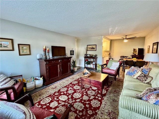 living room with ceiling fan, dark hardwood / wood-style floors, and a textured ceiling