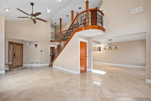 unfurnished living room featuring a towering ceiling and ceiling fan with notable chandelier