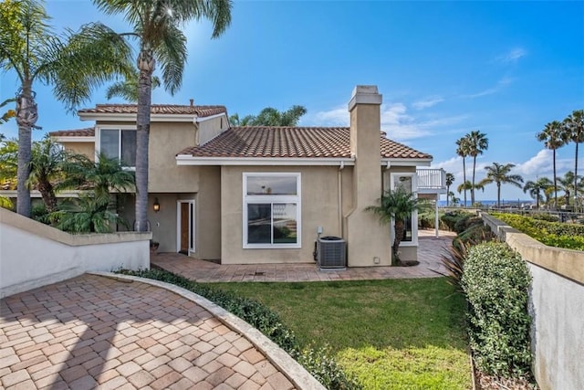 rear view of house featuring a balcony, central AC unit, a patio, and a lawn