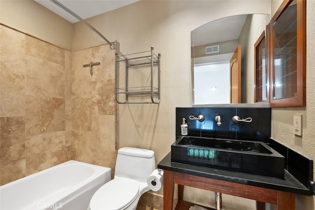 full bathroom featuring vanity, tiled shower / bath, and toilet