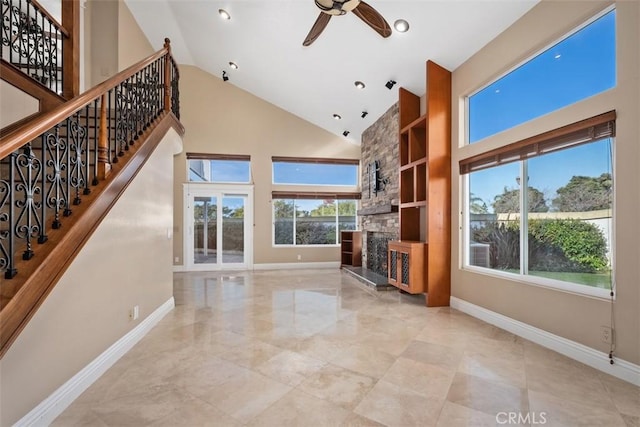 unfurnished living room with ceiling fan, high vaulted ceiling, and a fireplace