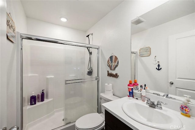 bathroom featuring vanity, toilet, and a shower with shower door