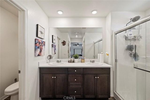 bathroom featuring vanity, a shower with door, and toilet