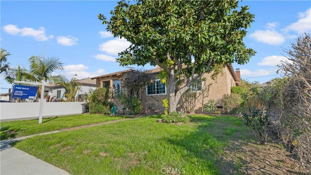 view of front of home featuring fence, a front lawn, and stucco siding