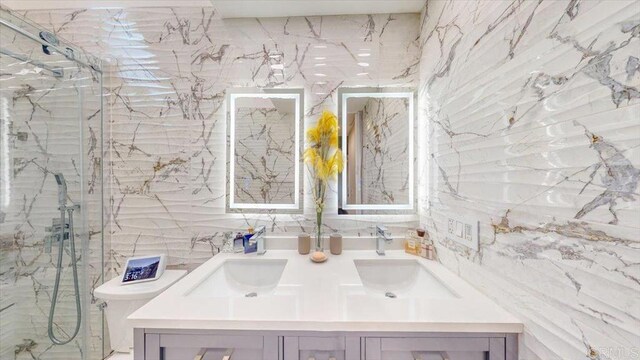 bathroom featuring a shower with door, vanity, and toilet