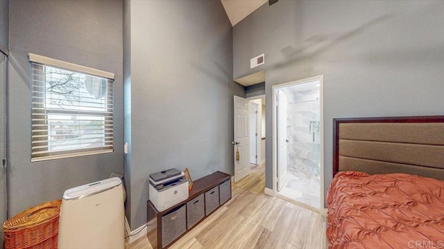 bedroom featuring ensuite bathroom, high vaulted ceiling, and light wood-type flooring