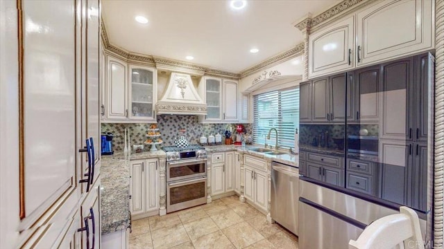 kitchen featuring sink, appliances with stainless steel finishes, decorative backsplash, custom exhaust hood, and dark stone counters