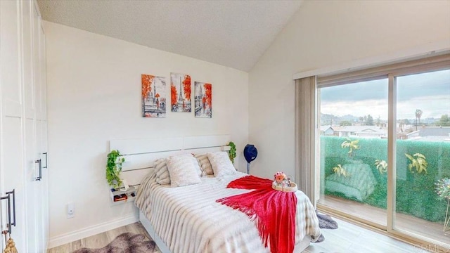 bedroom featuring hardwood / wood-style flooring, access to exterior, and vaulted ceiling