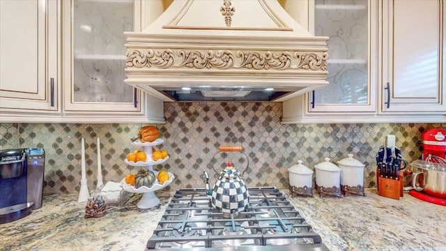 kitchen with premium range hood, tasteful backsplash, gas cooktop, light stone counters, and cream cabinets