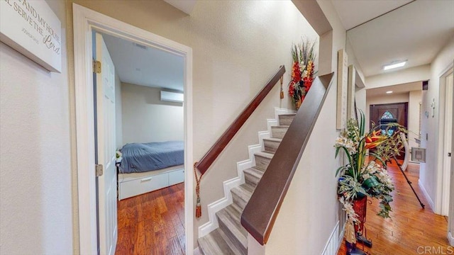 stairs with hardwood / wood-style flooring and an AC wall unit