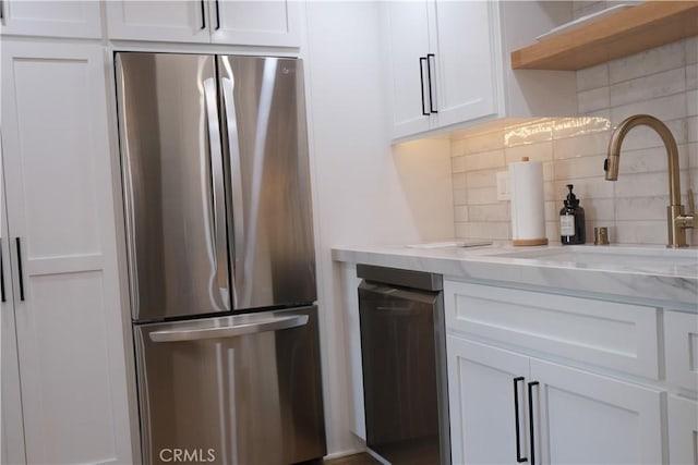 kitchen featuring stainless steel fridge, sink, decorative backsplash, and white cabinets