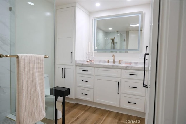 bathroom with hardwood / wood-style flooring, vanity, and a shower with door