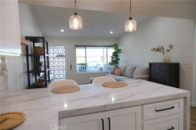 kitchen with decorative light fixtures, light stone countertops, and white cabinets