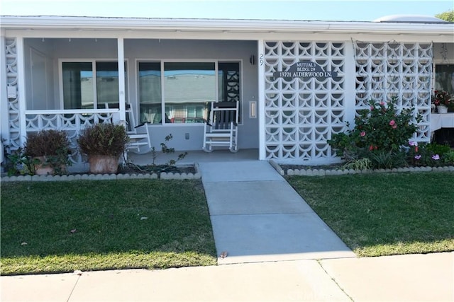 property entrance with a porch and a lawn