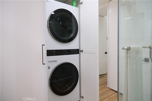 laundry room with stacked washer / dryer and light wood-type flooring