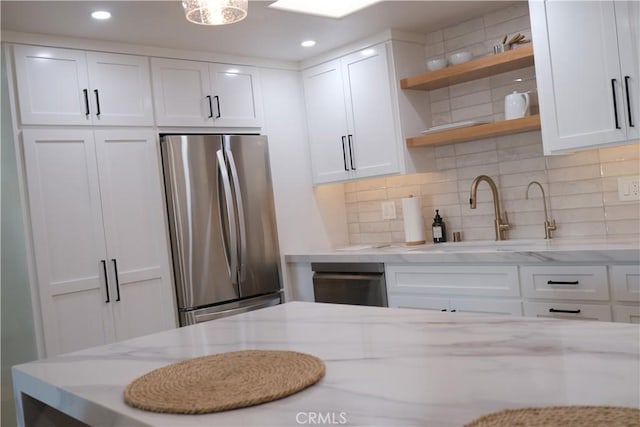 kitchen featuring white cabinetry, light stone countertops, and stainless steel fridge