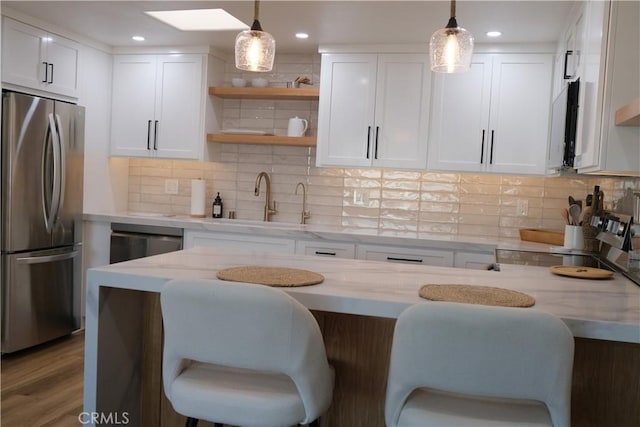 kitchen with white cabinetry, stainless steel appliances, hanging light fixtures, and light stone counters