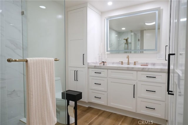 bathroom with toilet, a shower with door, and hardwood / wood-style floors