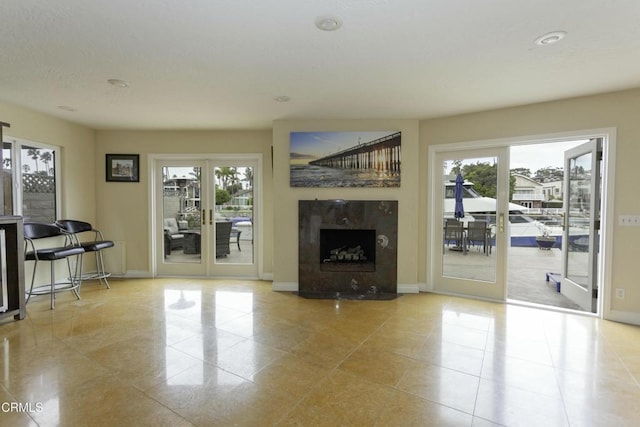 unfurnished living room with a tile fireplace, plenty of natural light, light tile patterned floors, and french doors