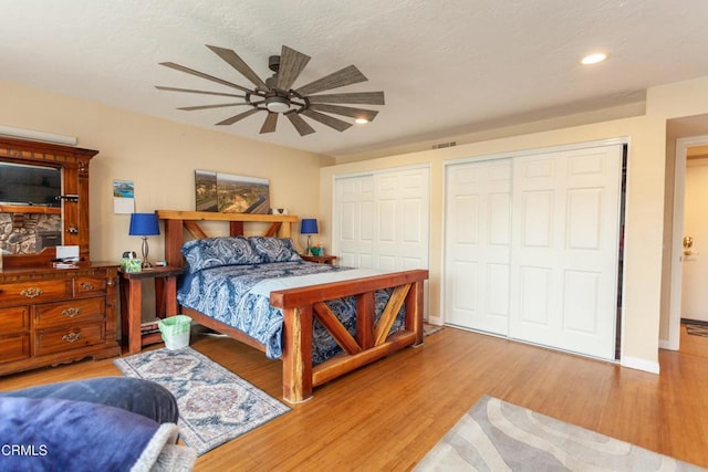 bedroom featuring hardwood / wood-style flooring, two closets, and ceiling fan