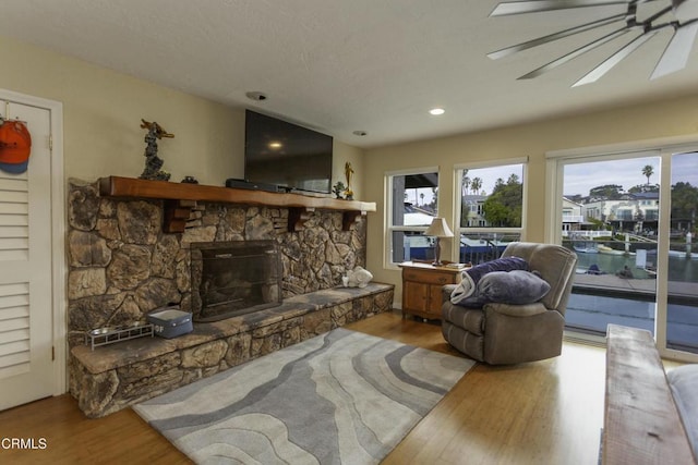 living room with ceiling fan, wood-type flooring, and a fireplace