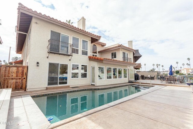rear view of house featuring a fenced in pool and a patio