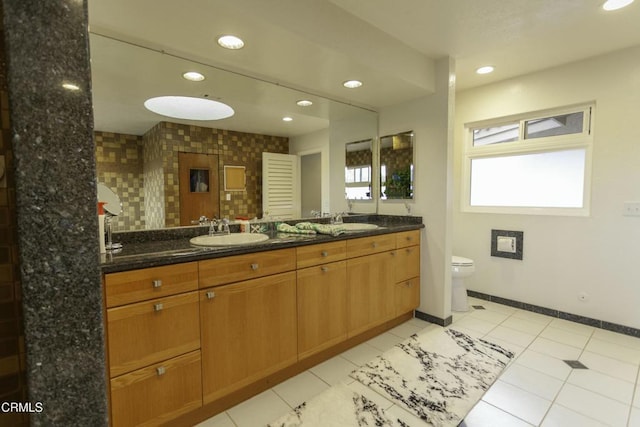 bathroom featuring tasteful backsplash, vanity, tile patterned flooring, and toilet