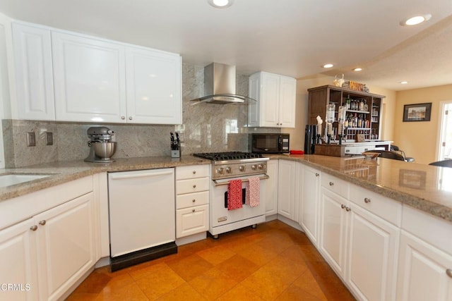 kitchen featuring tasteful backsplash, white cabinetry, light stone countertops, wall chimney range hood, and white appliances