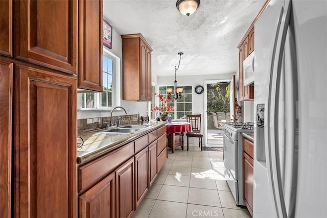 kitchen featuring pendant lighting, sink, white appliances, light tile patterned floors, and a chandelier