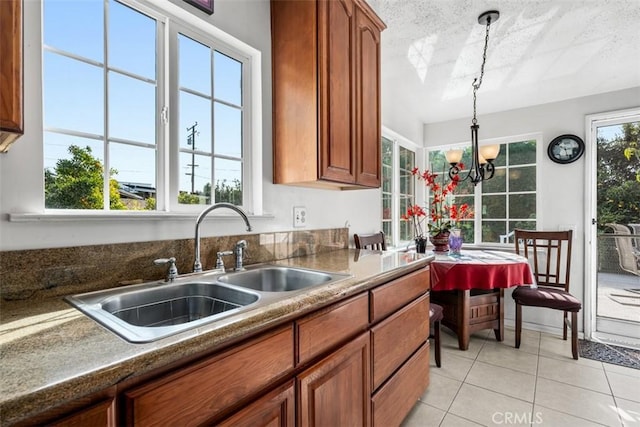 kitchen with light tile patterned flooring, decorative light fixtures, sink, a notable chandelier, and a healthy amount of sunlight