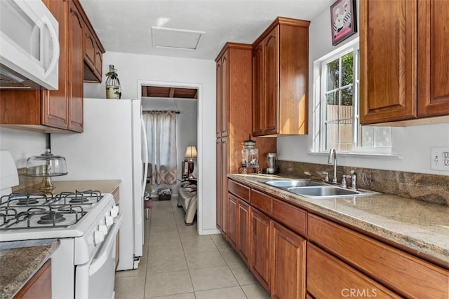 kitchen with light stone counters, sink, white appliances, and light tile patterned floors