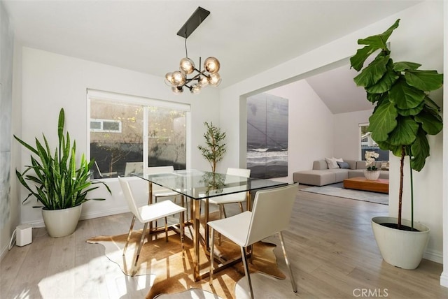 dining area with vaulted ceiling, hardwood / wood-style floors, and a chandelier