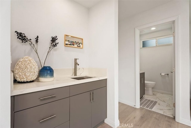 bar featuring gray cabinets, sink, and light wood-type flooring