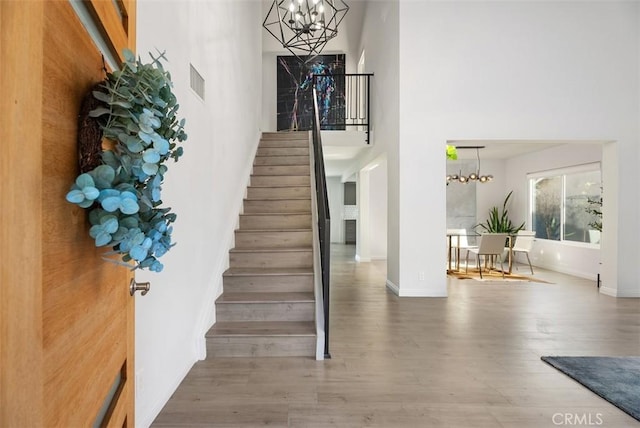 staircase featuring a high ceiling, hardwood / wood-style flooring, and a notable chandelier