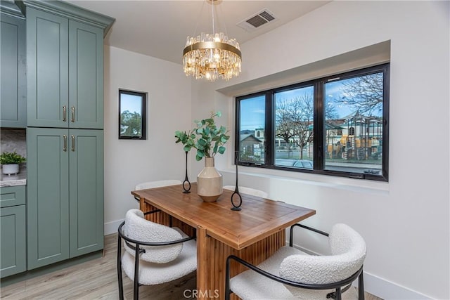 dining space featuring light hardwood / wood-style flooring and a notable chandelier