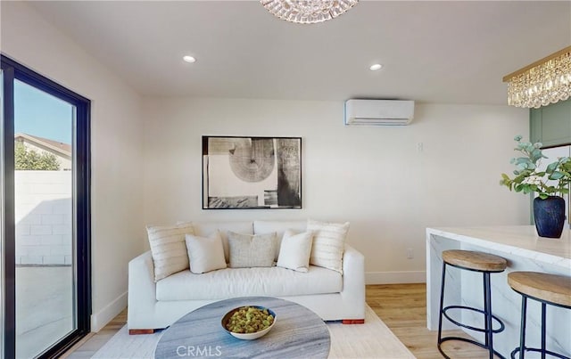 living room with a wall mounted air conditioner, an inviting chandelier, and light hardwood / wood-style flooring