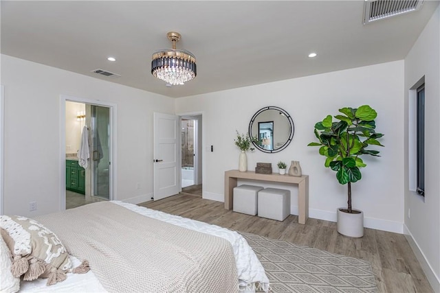 bedroom featuring a notable chandelier, ensuite bath, and light wood-type flooring