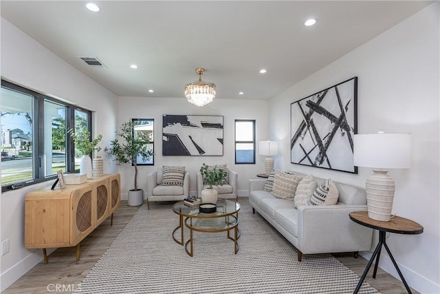 living room featuring a notable chandelier, light hardwood / wood-style flooring, and a healthy amount of sunlight