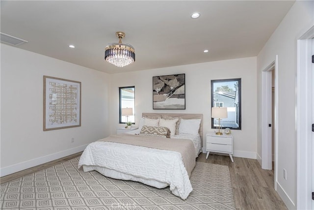 bedroom with an inviting chandelier, light hardwood / wood-style floors, and multiple windows