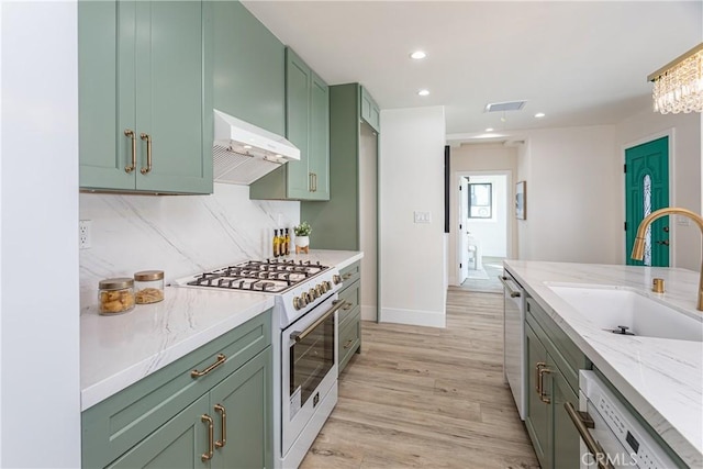 kitchen with sink, dishwasher, white range oven, green cabinetry, and wall chimney exhaust hood