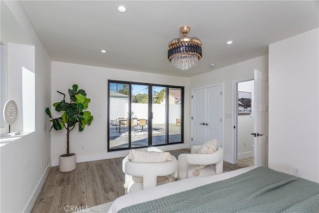 bedroom featuring an inviting chandelier, access to exterior, and light wood-type flooring