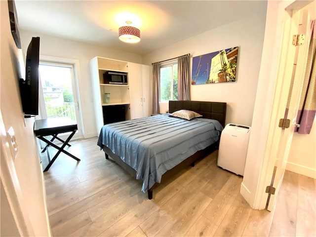 bedroom with access to outside and light wood-type flooring