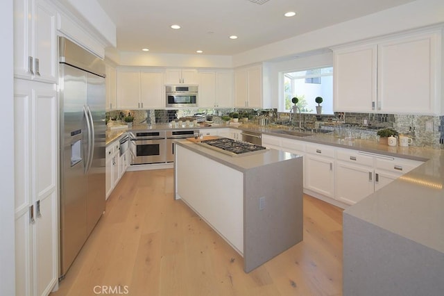 kitchen with a kitchen island, appliances with stainless steel finishes, sink, and white cabinets