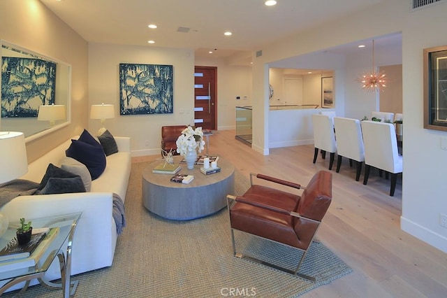 living room featuring an inviting chandelier and light hardwood / wood-style flooring