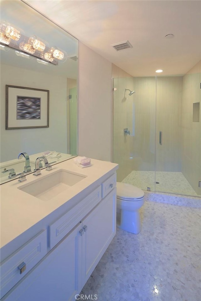 bathroom with vanity, a shower with shower door, and toilet