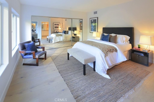 bedroom featuring multiple windows, light hardwood / wood-style flooring, and a closet