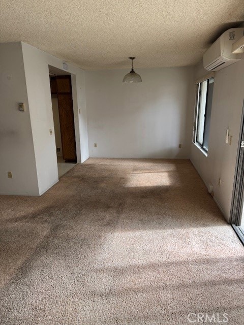 spare room featuring carpet, a textured ceiling, and a wall unit AC